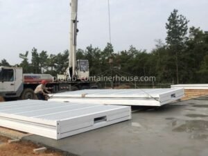 Crane unloading a folded prefab container house during the initial phase of site installation